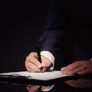 Foto de una persona firmando un documento para ilustrar el artículo "Pactos parasociales en una sociedad qué son, para qué sirven y cuál es su importancia", escrito por Gómez Garrido